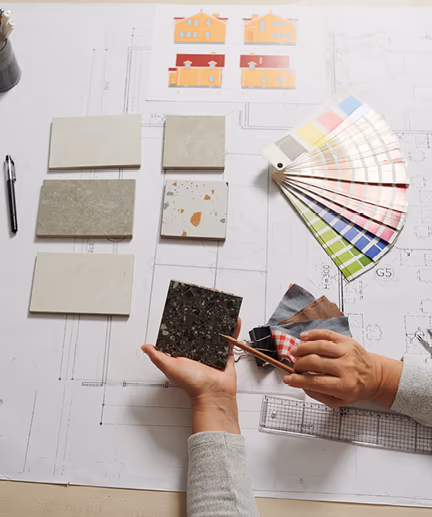 Technische Zeichnung einer Wohnung sowie verschiedene Farbmuster und Materialmuster liegen auf dem Tisch und werden verglichen.